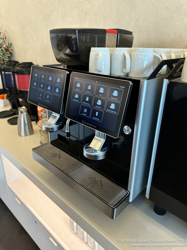 a coffee machine with a screen and coffee cups on a counter