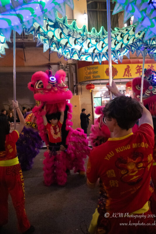 a group of people in a street with a lion dance