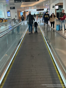 people walking down an airport walkway