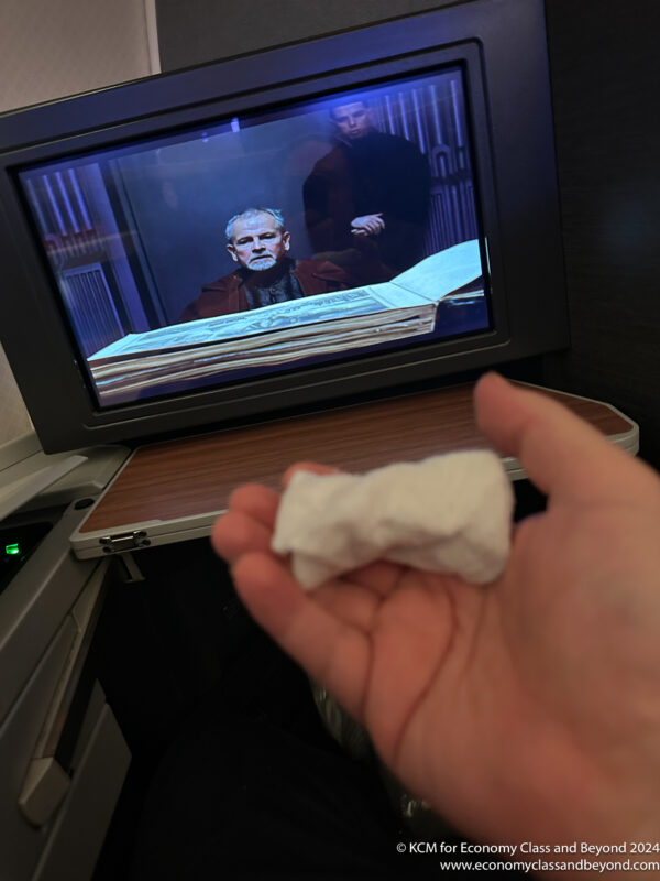 a hand holding a piece of tissue in front of a television
