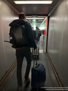 a man with a backpack pulling luggage in a hallway