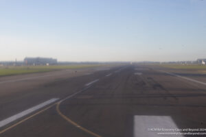 a runway with grass and buildings in the background
