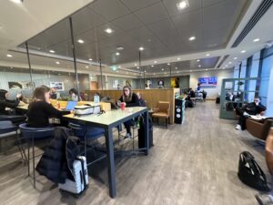 a group of people sitting at tables in a room with a glass wall