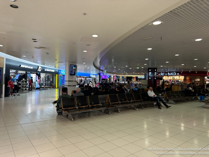 a group of people sitting in a row in a airport terminal