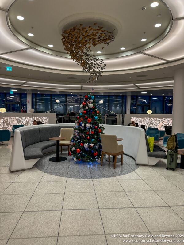 a christmas tree in a room with chairs and a table