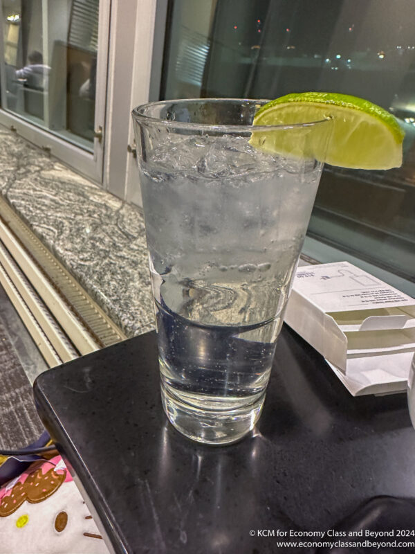 a glass of water with a lime wedge on a table