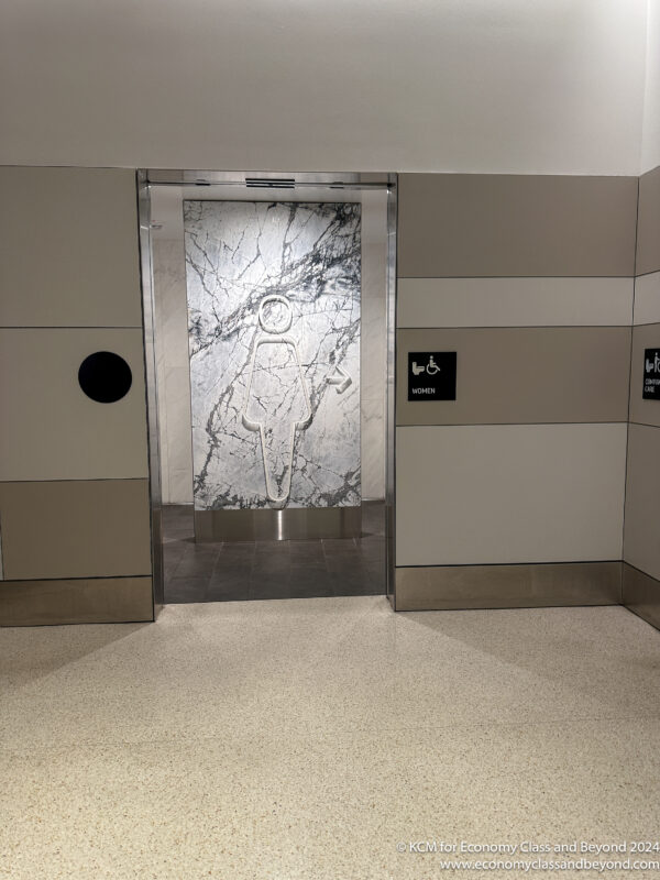 an elevator with a marble wall and a sign