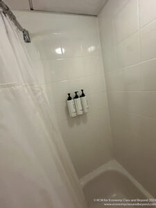a shower curtain and white tile wall with three bottles of shampoo