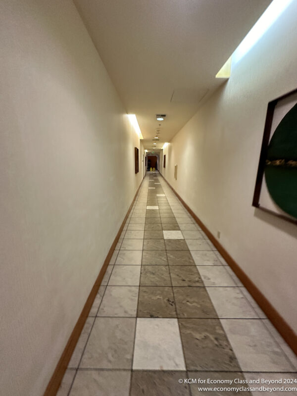 a long hallway with tile floor and a picture on the wall