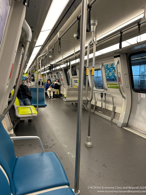 a train with blue seats and people sitting on the floor