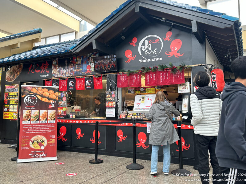 a small food stand with people standing in front of it
