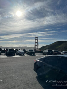 a parking lot with cars and a bridge in the background