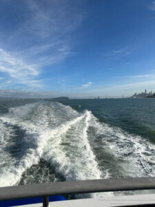 a wake of a boat in the water with a city in the background