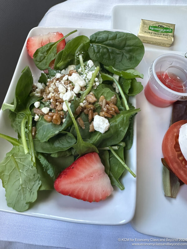 a plate of salad with strawberries and cheese