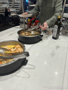 a man standing behind a counter with food in pots