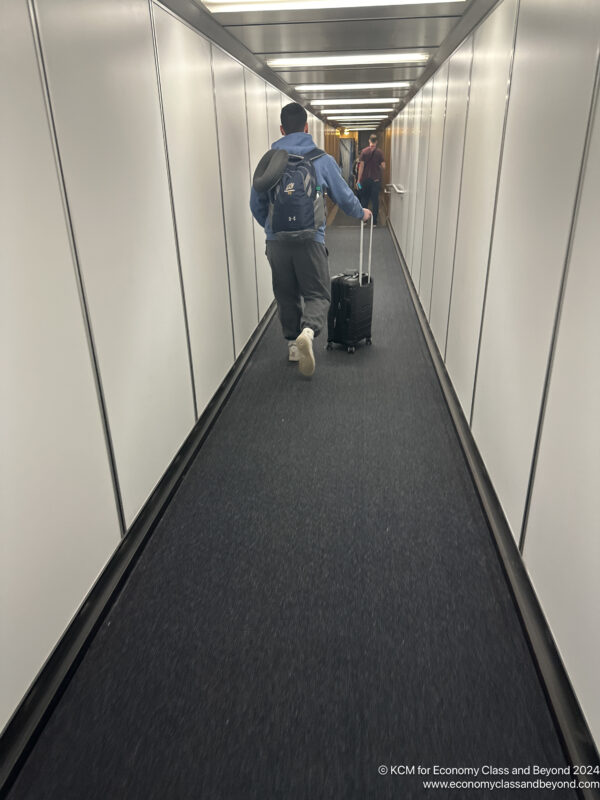 a man walking down a walkway with luggage