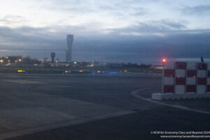 a runway with lights on and a tower in the background