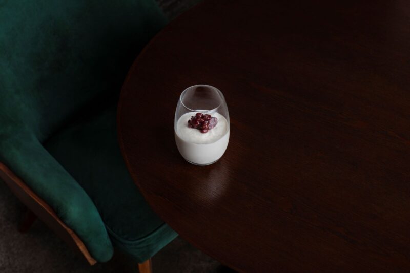 a glass of white liquid with a berry on top of it