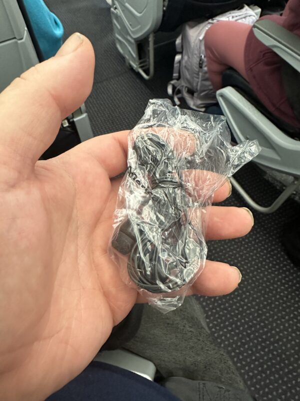 a hand holding a plastic bag of earbuds