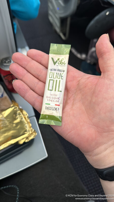 a hand holding a small packet of olive oil