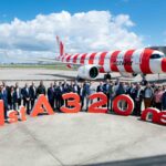 a group of people standing in front of a large red and white airplane