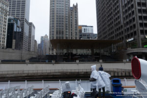 people wearing white raincoats and standing on a boat in a city