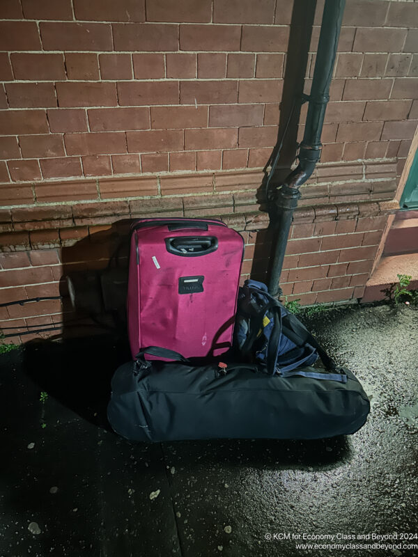 a pink suitcases next to a brick wall