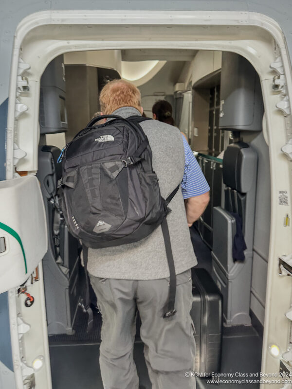 a man with a backpack walking in an airplane