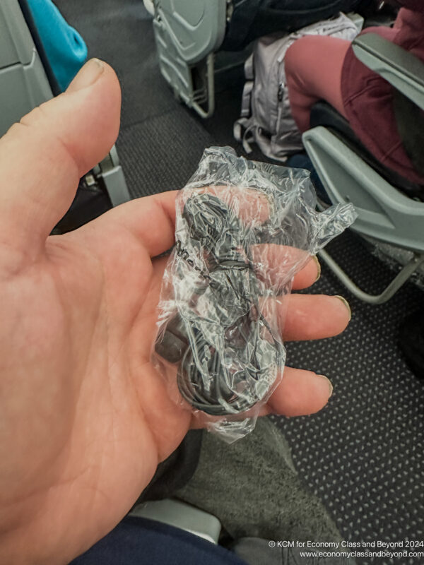 a hand holding a black cord in a plastic wrap