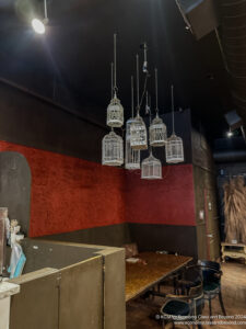 a room with a table and bird cages from the ceiling