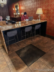 a man and woman sitting at a bar with laptops