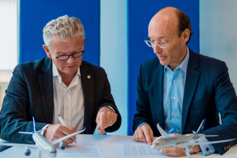 two men sitting at a table signing a document