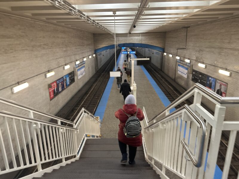a woman walking up stairs in a subway station