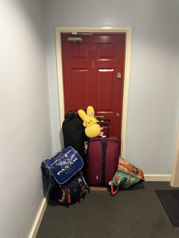a red door with luggage and a stuffed bear