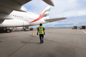 a man walking on a runway with a large airplane