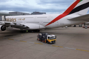 a large white airplane with a yellow truck on the tarmac