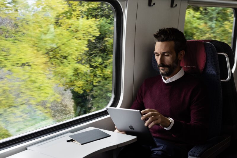 a man sitting in a train using a tablet