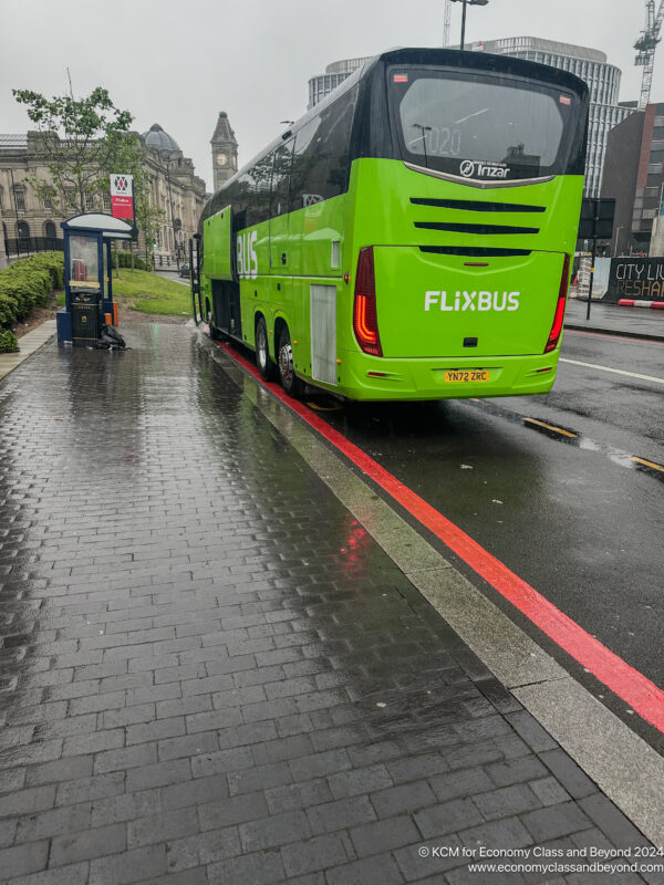 a green bus on a wet street