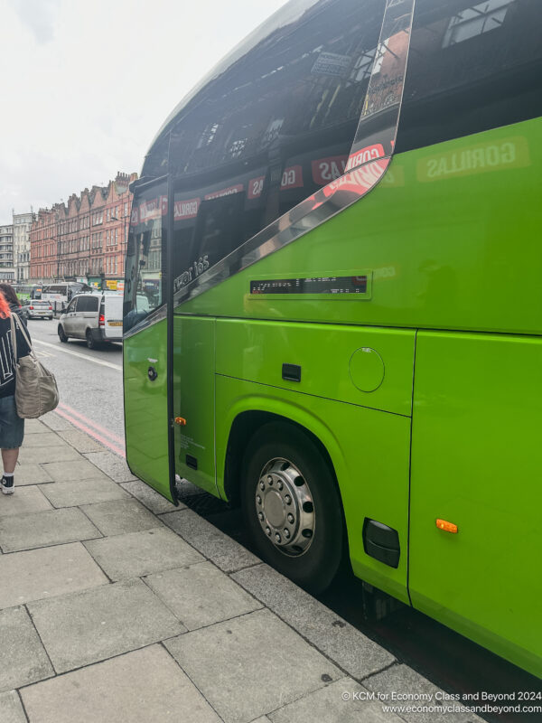 a green bus parked on a sidewalk