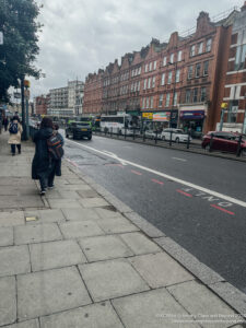 a woman walking on a sidewalk next to a street with buildings