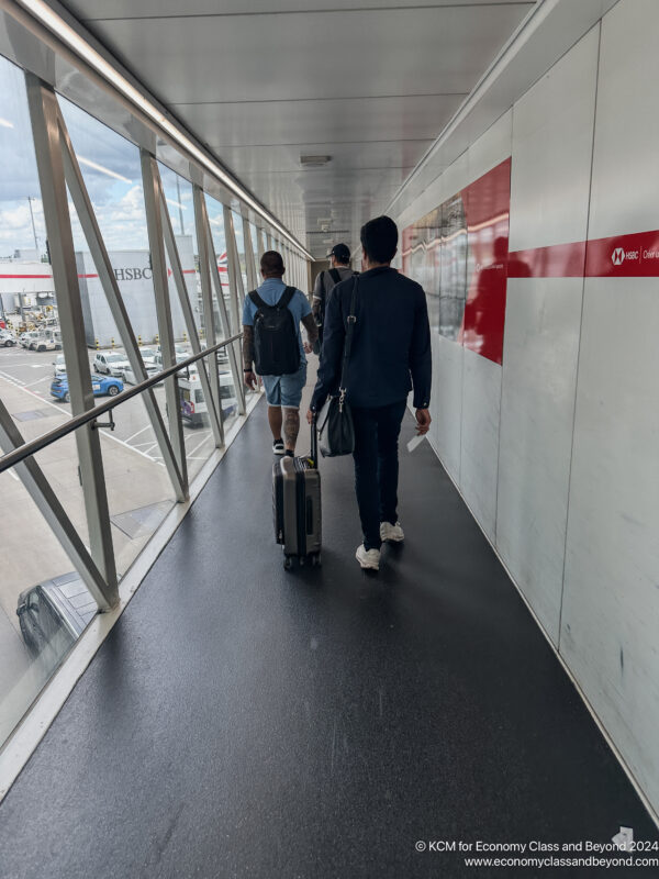 a group of people walking down a walkway with luggage