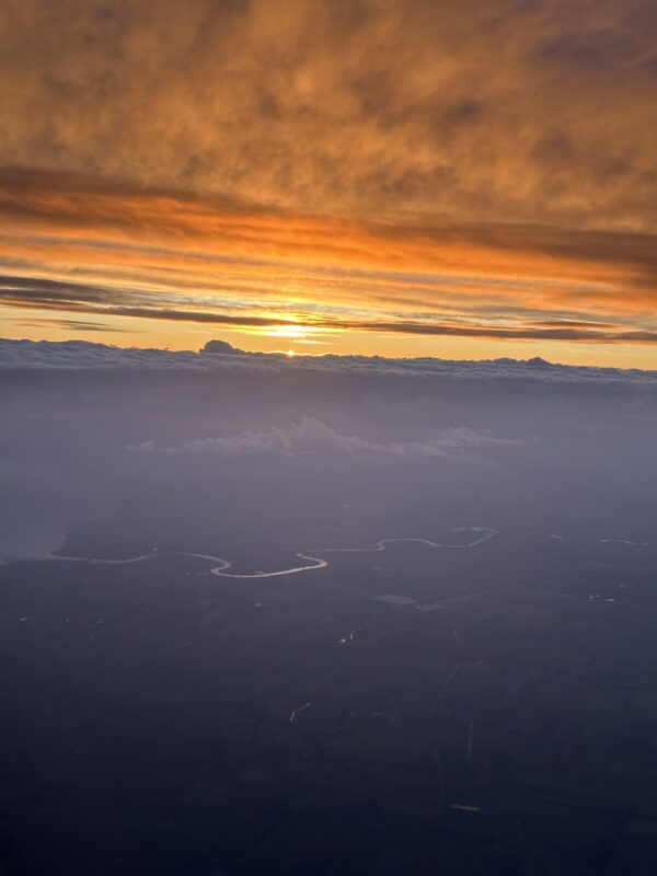 a sunset over clouds and a river