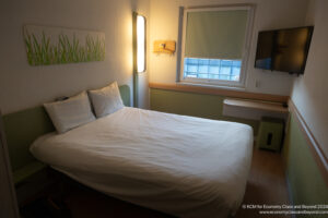 a bed with a white sheet and a tv on the wall