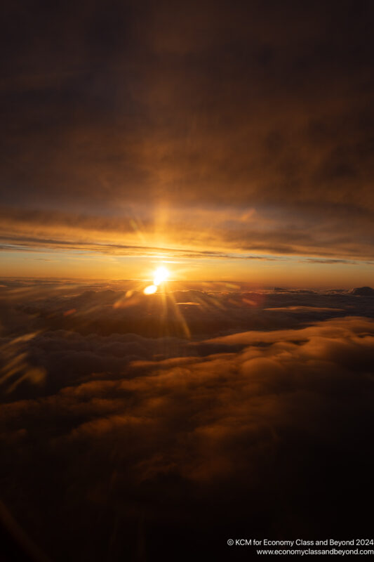 a sunset over clouds and a large body of water