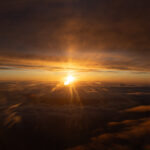 a sunset over clouds and a city