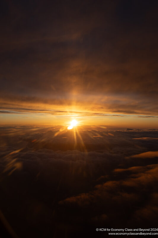 a sunset over clouds and a city