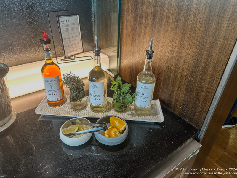 bottles of liquid and a bowl of fruit on a counter