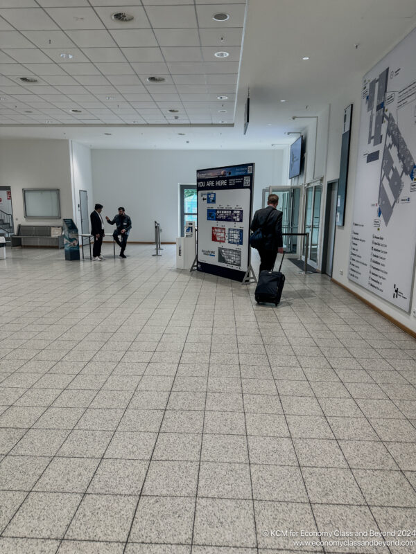 people in a building with a large white board and a man with luggage