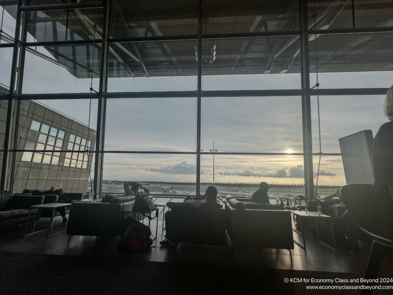 a group of people sitting in a room with large windows