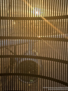 a sun shining through a metal fence